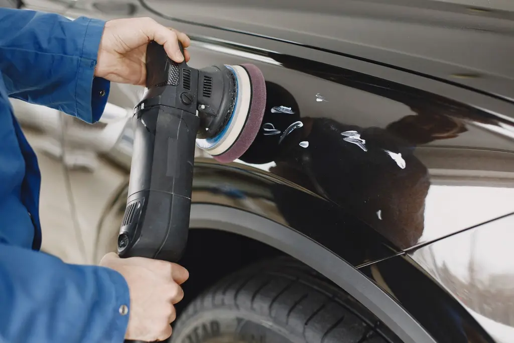 A professional carefully machine polishing the paintwork of a car